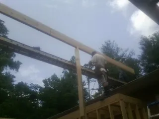 Carpenter setting a ridge beam over a new addition frame — Ice Dam Removal by Roofing Brothers in Tomball