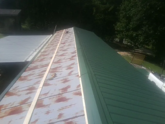 Old rusted panels beside newly installed green metal roofing — Wind Damage Roof Repair by Roofing Brothers in Tomball