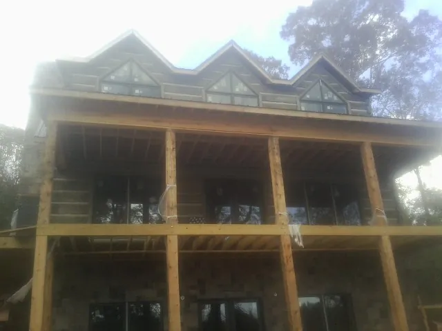 Dormers and porch framing on a large log home under construction — Roof Coating work by our crew in Tomball