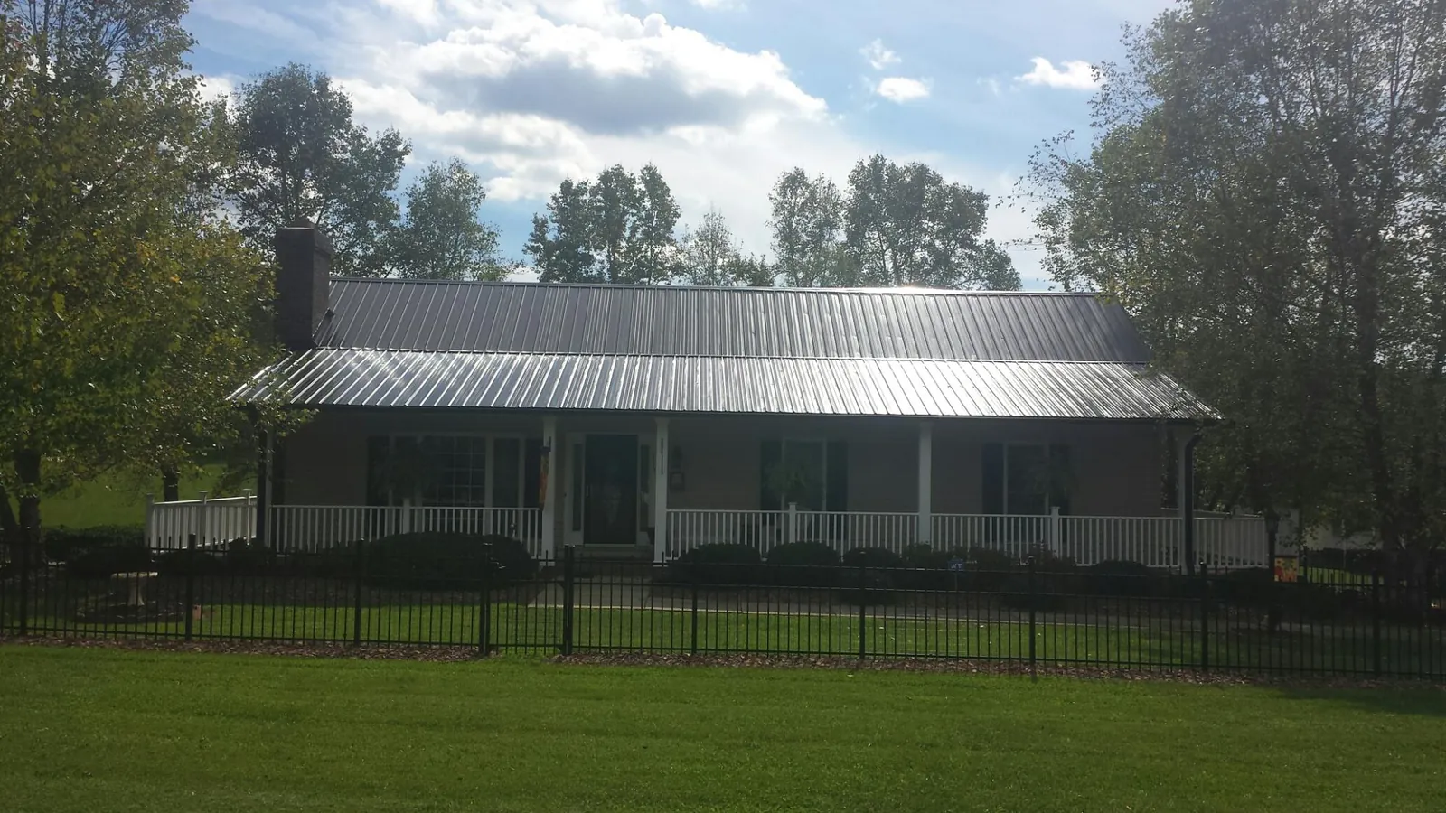 Gray metal roof on a brick ranch with a full width front porch — Gutter Guard Installation work by our crew in Tomball