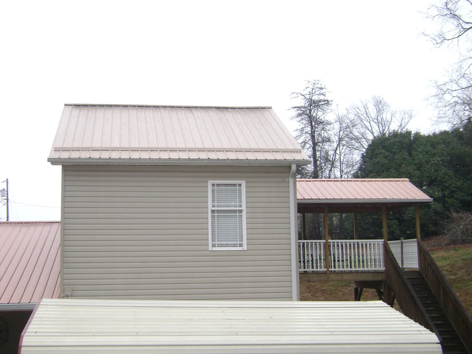 Tan metal roofs on a two story addition and attached porch, from a Roof Replacement job in Tomball